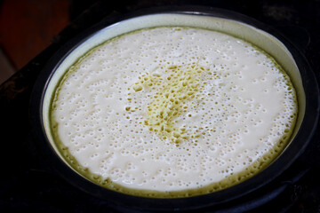 Close-up of batter frying in the early stage of making Indonesian sweet martabak, showing bubbles forming on the surface.