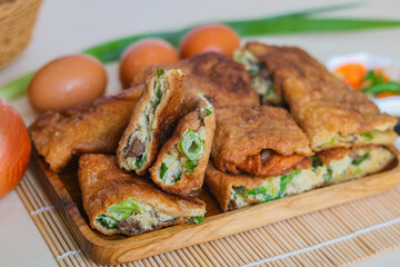 Close-up of a platter of freshly sliced Martabak Telor (Indonesian egg pancake). The filling is typically made with egg, minced beef, and chopped scallions. An iconic street food for a meal or snack.