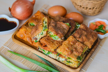 Top view of a platter of freshly sliced Martabak Telor (Indonesian egg pancake). The filling is typically made with egg, minced beef, and chopped scallions. An iconic street food for a meal or snack.