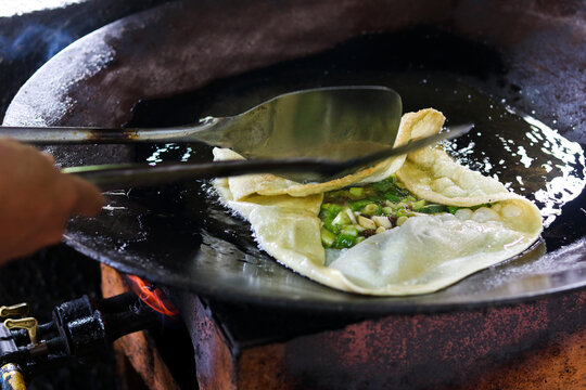Person making Martabak Telor (Indonesian egg pancake) at a local street food stall.&nbsp;The filling is typically made with egg, minced beef, and chopped scallions, sizzling to perfection.&nbsp;