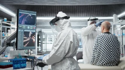 Doctor in quarantine performing clinical study on an infectious patient, testing vaccine responses and monitoring DNA molecules on monitor to develop treatments for epidemics. Camera A. - Powered by Adobe