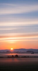 Naklejka premium Sunrise over misty fields and rolling hills.