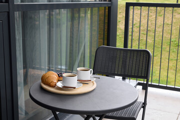A Cozy Balcony Breakfast Setting complete with a fresh Cup of Coffee and a Croissant