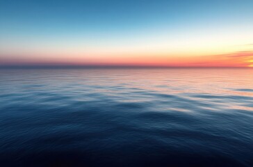 Obraz premium Calm ocean water under a clear sky with a colorful sunset on the horizon creating a peaceful and serene atmosphere