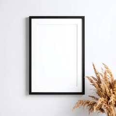 A rustic vase filled with an assortment of dried flowers in muted tones sits beside an elegant, empty picture frame, inviting creativity and nostalgia.