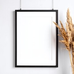 A rustic vase filled with an assortment of dried flowers in muted tones sits beside a blank white poster, creating a serene and minimalist aesthetic.