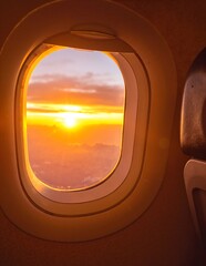 A breathtaking view of a vibrant sunset seen through an airplane window, with hues of orange, pink, and purple blending beautifully in the sky.