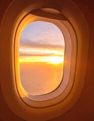 A breathtaking view of a vibrant sunset from an airplane window, showcasing hues of orange, pink, and purple blending across the sky, with fluffy clouds below.