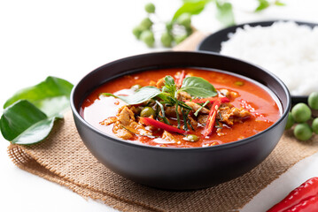 Thai red curry with pork and cooked rice with ingredients on white background