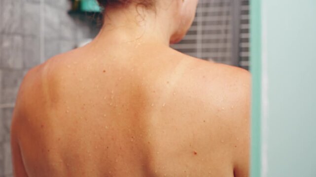 Wet Bare Back of Woman in Shower with Water Droplets on Skin and Tiled Wall in Background, Close-Up Rear View, Cleanliness and Wellness Concept