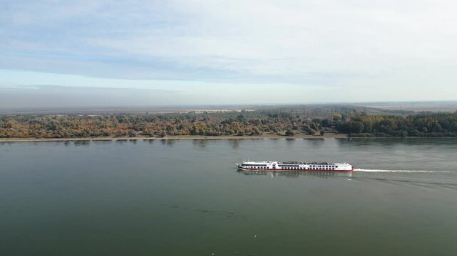 A large white tourist cruise ship sailing along the Danube River through the scenic Srem region of Serbia, with beautiful natural landscapes in the background. Srem, Serbia, 14.10.2025

