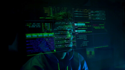 Anonymous hacker wearing a mask and hoodie interacting with digital data in a dark room
