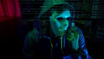 Anonymous hacker wearing a mask and hoodie interacting with digital data in a dark room