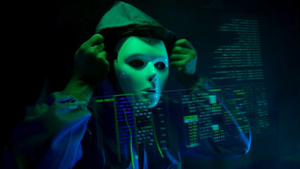 Anonymous hacker wearing a mask and hoodie interacting with digital data in a dark room