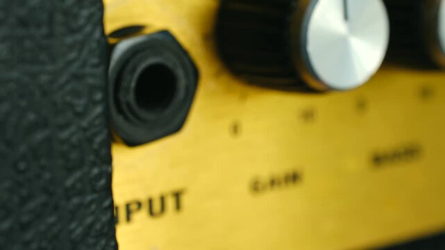 Closeup musician hand unplugging golden jack cable from input guitar amplifier, finishing rehearsal or concert session in music studio or on stage. Musician unplugging guitar jack cable from amplifier