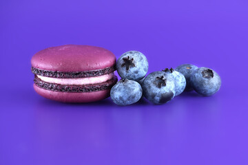 Macarons and blueberries over purple background