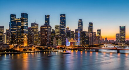 Fototapeta premium The city skyline of Guangzhou, China, with modern skyscrapers illuminated at dusk, reflected in the water of the Pearl River.