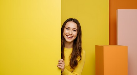 Smiling woman peeking from behind a yellow wall.