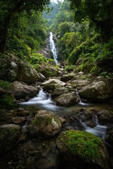 Fototapeta premium a serene natural scene of a flowing waterfall surrounded by lush greenery and boulders, all under the vastness of a clear sky