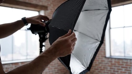 Photographer Adjusting Softbox Light Modifier in Studio.
