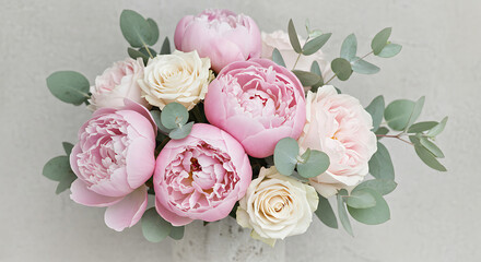 A beautiful bouquet of pink peonies and white roses with eucalyptus leaves, arranged on a light gray background.