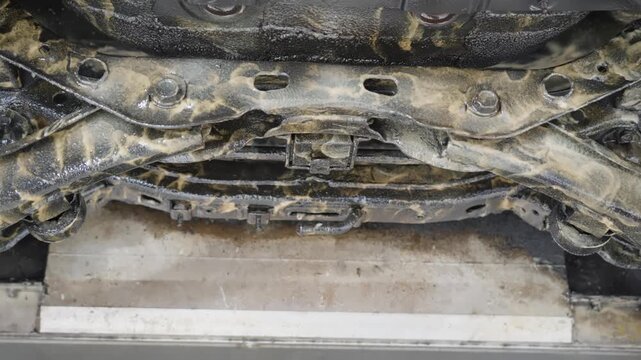 Close up low angle sliding view of electric vehicle underside after lanolin rust protection treatment.