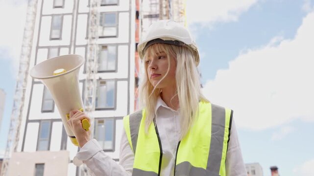 Young female construction worker instructs team on busy site in bright safety gear