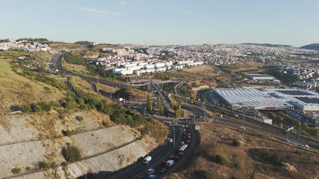 Drone aerial over Amadora, Portugal showing Av. Eduardo Malta, UBBO mall, city traffic, and surrounding urban landscape near Parque das Artes e do Desporto.