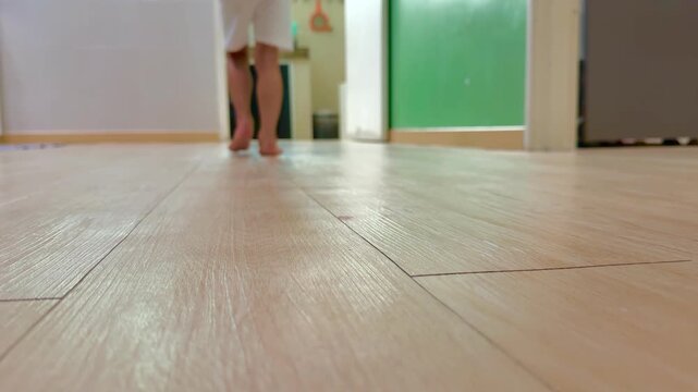 Person in red shirt walking down wooden hallway