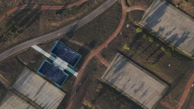 Drone aerial over Parque das Artes e do Desporto in Amadora, Portugal showing tennis courts, football fields, and surrounding green park area.