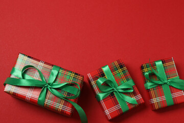 Top view of Christmas gifts with decorations and fir branches on red background
