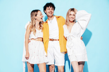 Young three stylish friends posing in studio. Fashion man and two cute female dressed in casual...