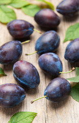 Ripe purple plums fallen on wooden table