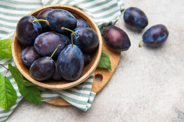 Fresh ripe plums filling a wooden bowl