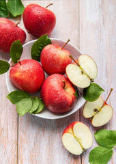 Fresh red apples with water drops and green leaves