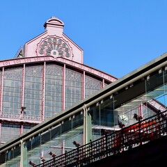 Antwerp Central station architecture detail showing ornate ironwork, glass walls, a pedestrian bridge, and clock under blue sky