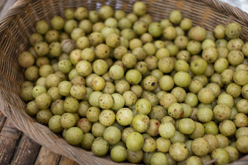 Several Indian gooseberry fruits in a wicker basket