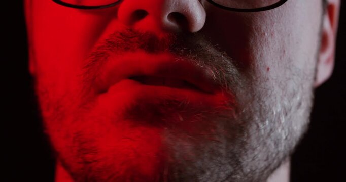 A close-up of a man&rsquo;s face under dramatic red lighting shows him biting his lip slightly, symbolizing tension, anticipation, or inner conflict in a cinematic moment