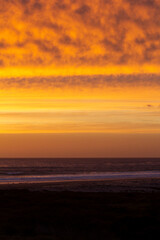 Cloudy golden sunset over Pacific Ocean and sandy beach.