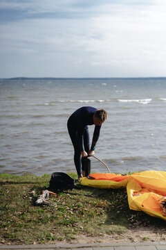 Kitesurfer preparing gear and pumping up kite on grassy shore