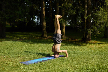 Practicing yoga headstand in a peaceful green park setting