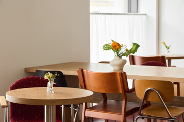 Cozy cafe interior with tables and fresh flowers during daytime