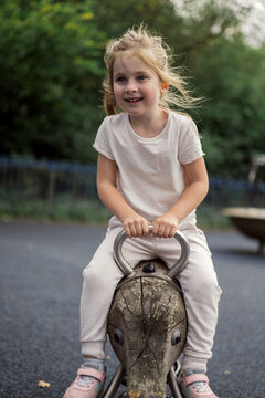 Little girl riding a wooden rocking toy on playground