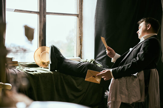 Gentleman relaxing indoors while reading letters at a window