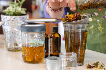 Straining dried herbs into oil during herbal infusion process