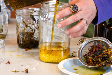 Pouring infused herbal oil into beeswax for homemade salve