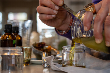 Woman pours finished herbal salve into small container