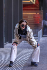 Obraz premium A young brunette in light warm clothes on the streets of an autumn city.