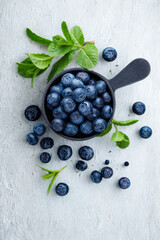 Fresh blueberries piled in a small black scoop with mint leaves