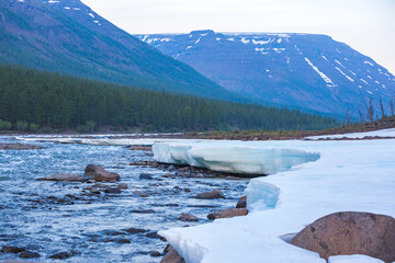 Snow and ice on the banks of the river Hoisey. Polar day on Putorana Plateau